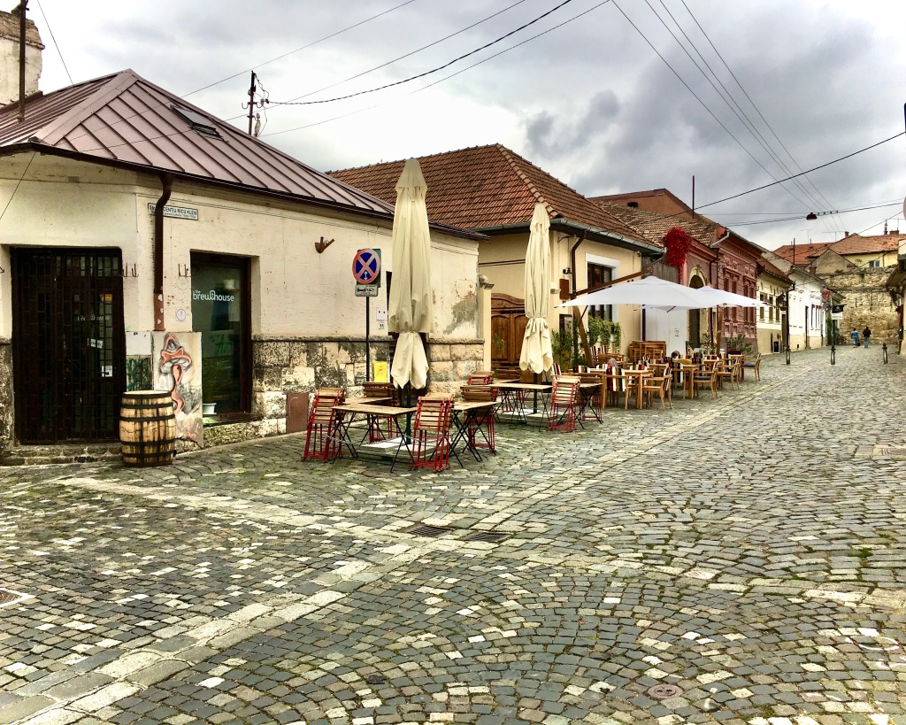 Restaurants along a cobblestone street in Cluj